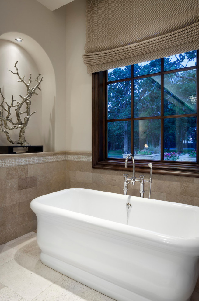 Diseño de cuarto de baño principal actual de tamaño medio con bañera exenta, paredes beige, suelo de piedra caliza y suelo beige