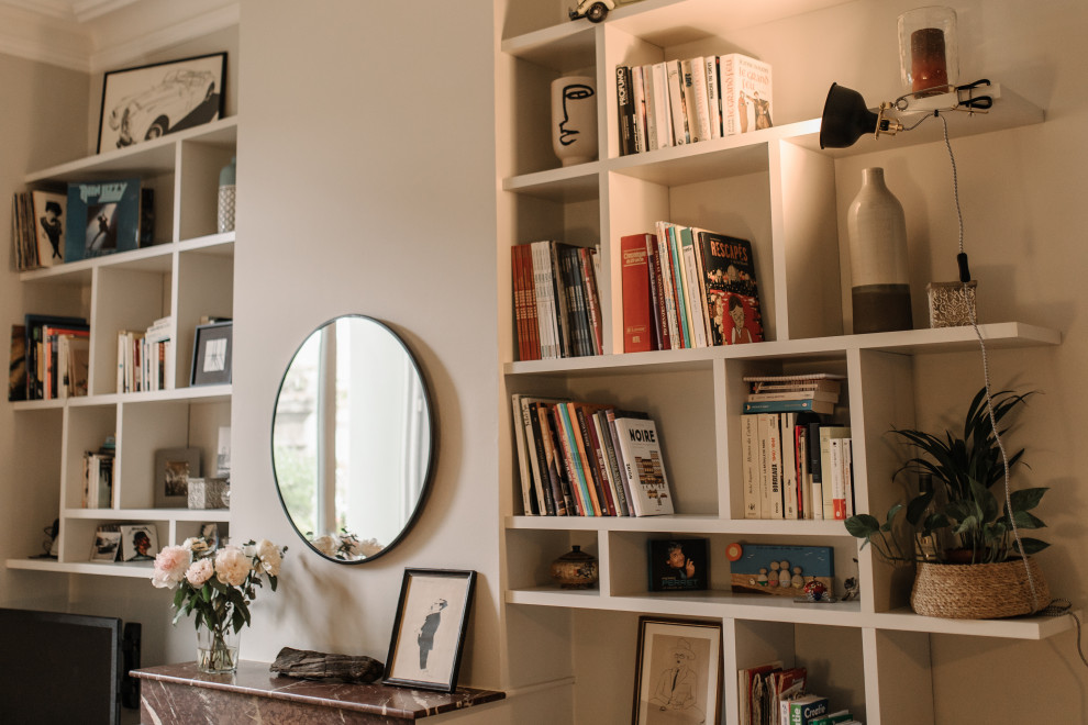 Esempio di un grande soggiorno minimal aperto con libreria, pareti beige, pavimento in legno massello medio, camino classico e parete attrezzata