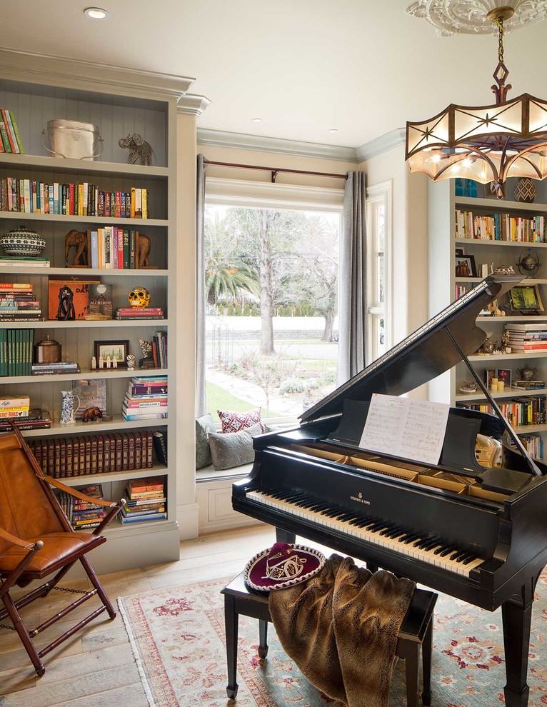 This is an example of a mid-sized traditional enclosed living room in San Francisco with a library, green walls, light hardwood floors and no tv.