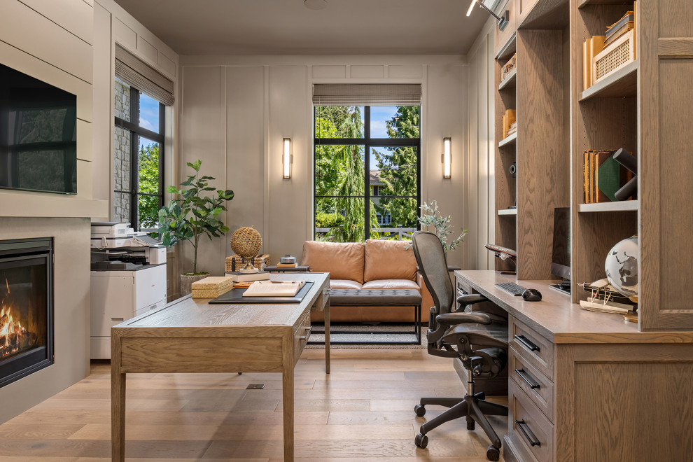 Klassisches Arbeitszimmer mit Arbeitsplatz, grauer Wandfarbe, braunem Holzboden, Kamin, Kaminumrandung aus Holzdielen, freistehendem Schreibtisch und vertäfelten Wänden in Seattle