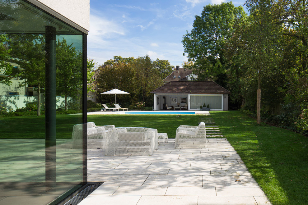 This is an example of an expansive contemporary backyard partial sun garden for summer in Munich with a garden path and concrete pavers.
