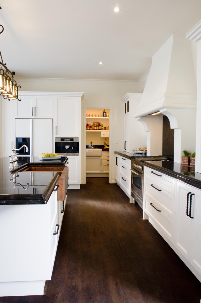 Inspiration for a mediterranean kitchen in Los Angeles with a farmhouse sink, recessed-panel cabinets, white cabinets, granite benchtops and stainless steel appliances.