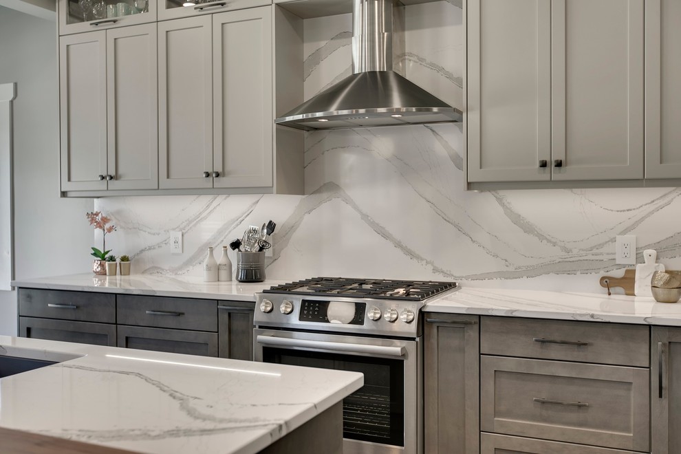 Large transitional u-shaped dark wood floor and brown floor eat-in kitchen photo in Calgary with an undermount sink, recessed-panel cabinets, gray cabinets, quartzite countertops, white backsplash, stone slab backsplash, stainless steel appliances, an island and white countertops