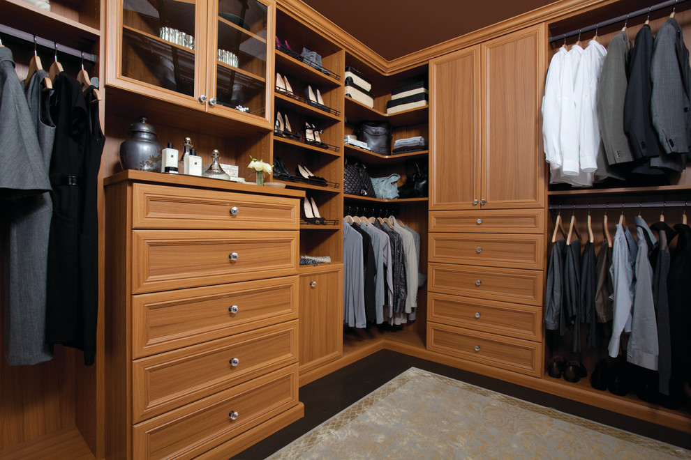 Inspiration for a large traditional gender-neutral walk-in wardrobe in Austin with recessed-panel cabinets, medium wood cabinets and carpet.