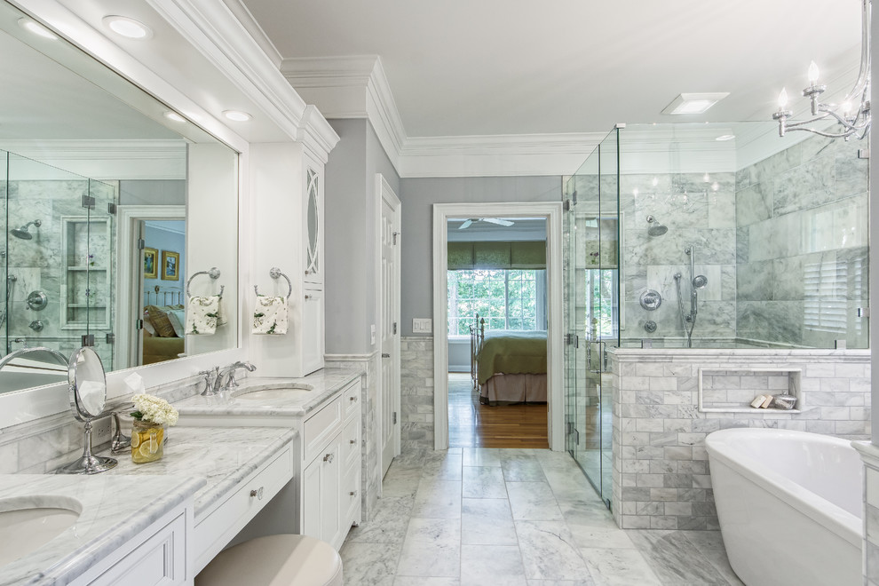 Photo of a traditional master bathroom in Columbus with beaded inset cabinets, white cabinets, a freestanding tub, a curbless shower, marble, grey walls, marble floors, an undermount sink, marble benchtops, grey floor and a hinged shower door.