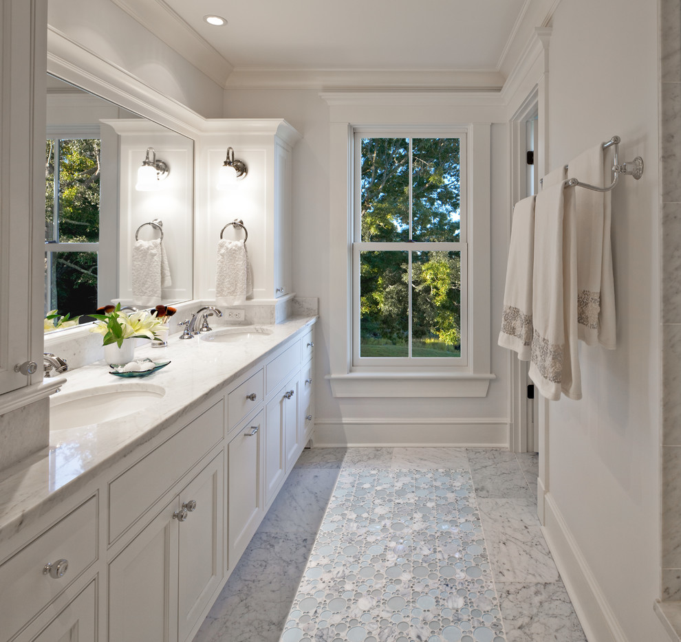Photo of a beach style master bathroom in Providence with recessed-panel cabinets, white cabinets, white walls, marble floors, an undermount sink, marble benchtops, multi-coloured floor and white benchtops.