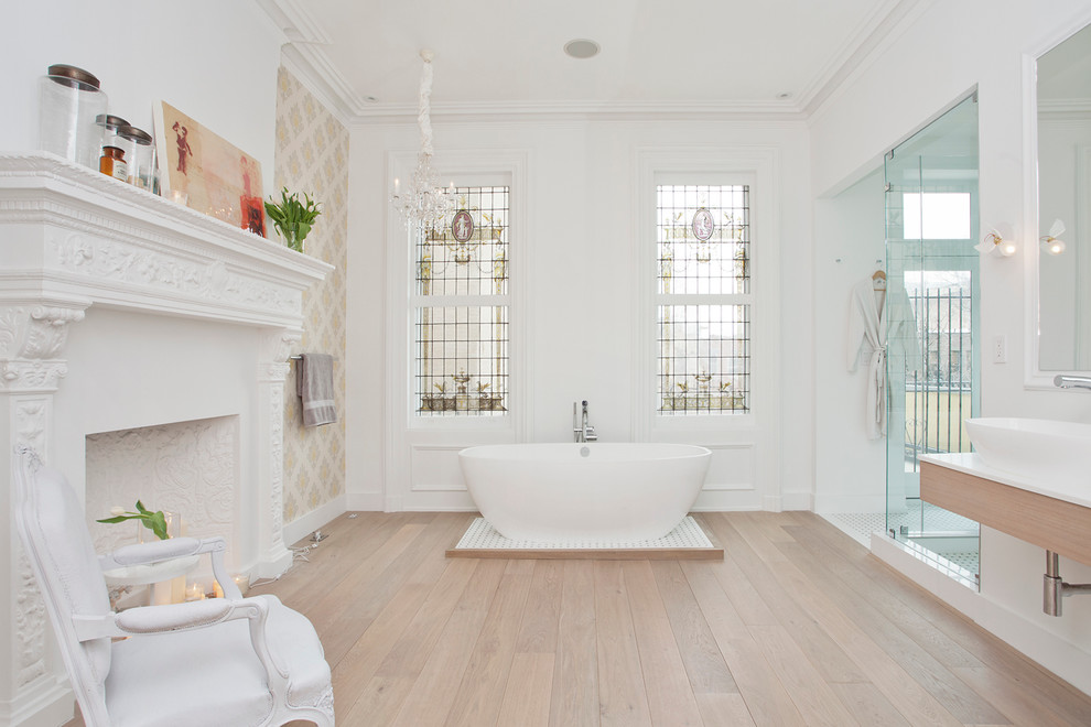 Photo of a large traditional master bathroom in New York with a vessel sink, a freestanding tub, an alcove shower, white walls, light hardwood floors, flat-panel cabinets and light wood cabinets.