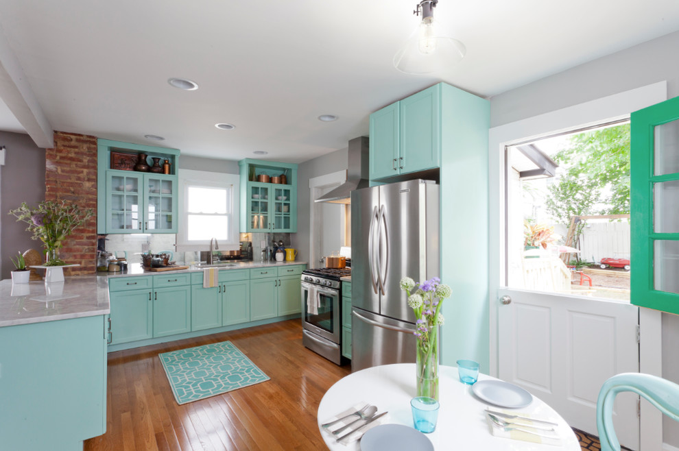 Arts and crafts u-shaped eat-in kitchen in New York with an undermount sink, glass-front cabinets, blue cabinets, quartzite benchtops, mirror splashback and stainless steel appliances.