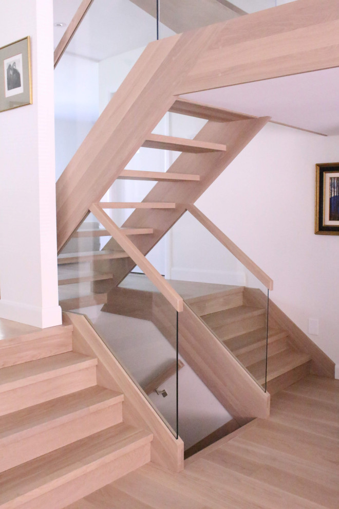 Modern wood staircase in Montreal with wood risers and glass railing.