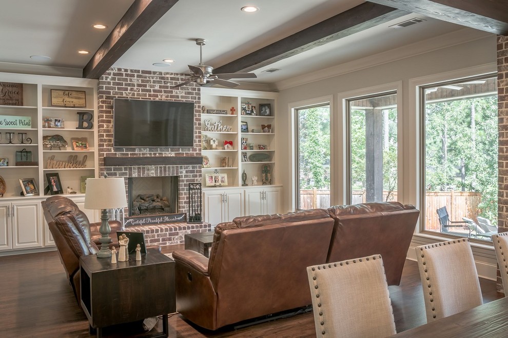 This is an example of a transitional open concept family room in Other with grey walls, vinyl floors, a standard fireplace, a brick fireplace surround, a wall-mounted tv and brown floor.