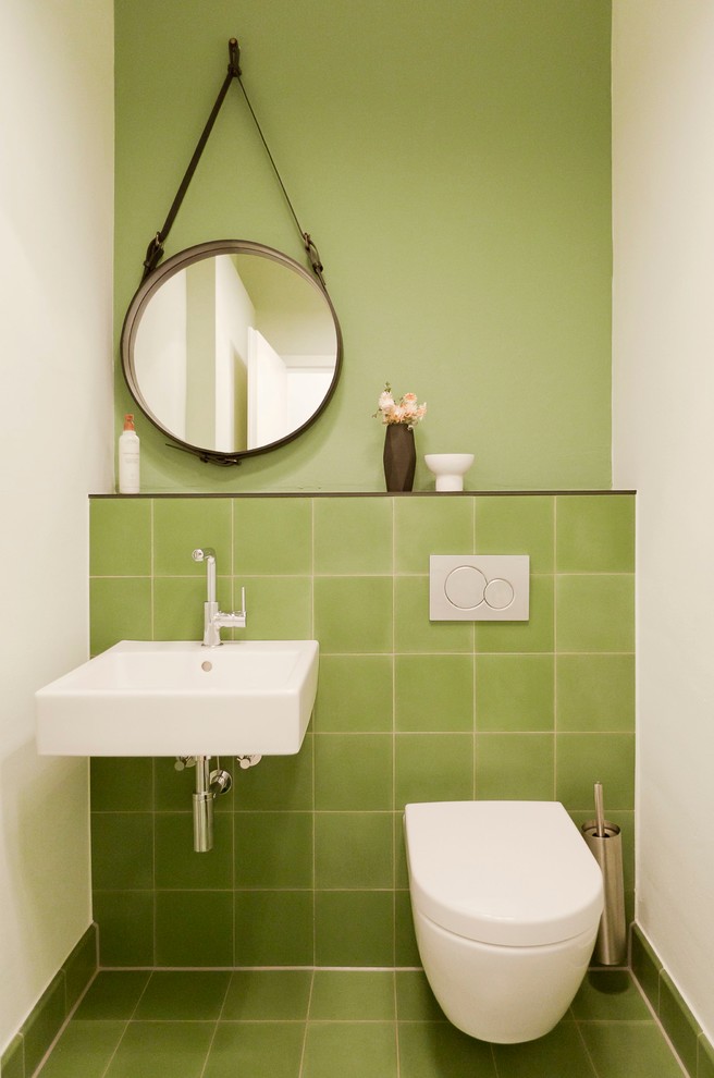 This is an example of a small contemporary powder room in Frankfurt with a wall-mount sink, a wall-mount toilet, green tile, green walls, porcelain floors and porcelain tile.