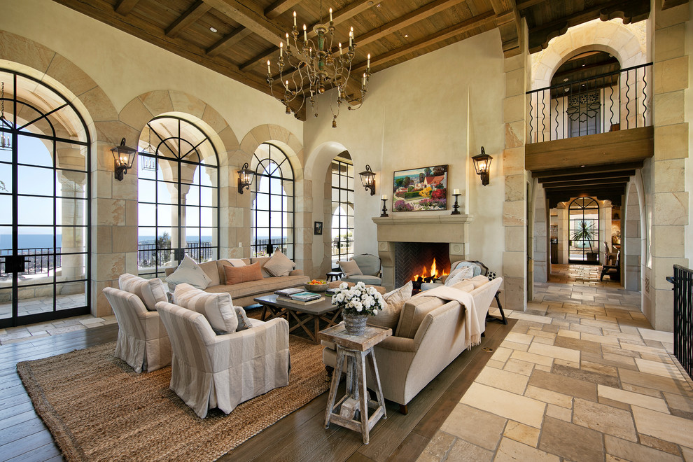 Inspiration for a large mediterranean formal open concept living room in Santa Barbara with beige walls, limestone floors, a standard fireplace, a stone fireplace surround, no tv and beige floor.
