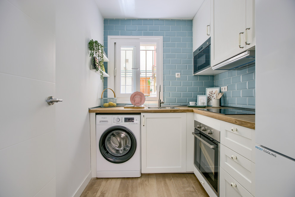 This is an example of a small scandinavian l-shaped separate kitchen in Madrid with an undermount sink, beaded inset cabinets, white cabinets, wood benchtops, blue splashback, ceramic splashback, white appliances and ceramic floors.