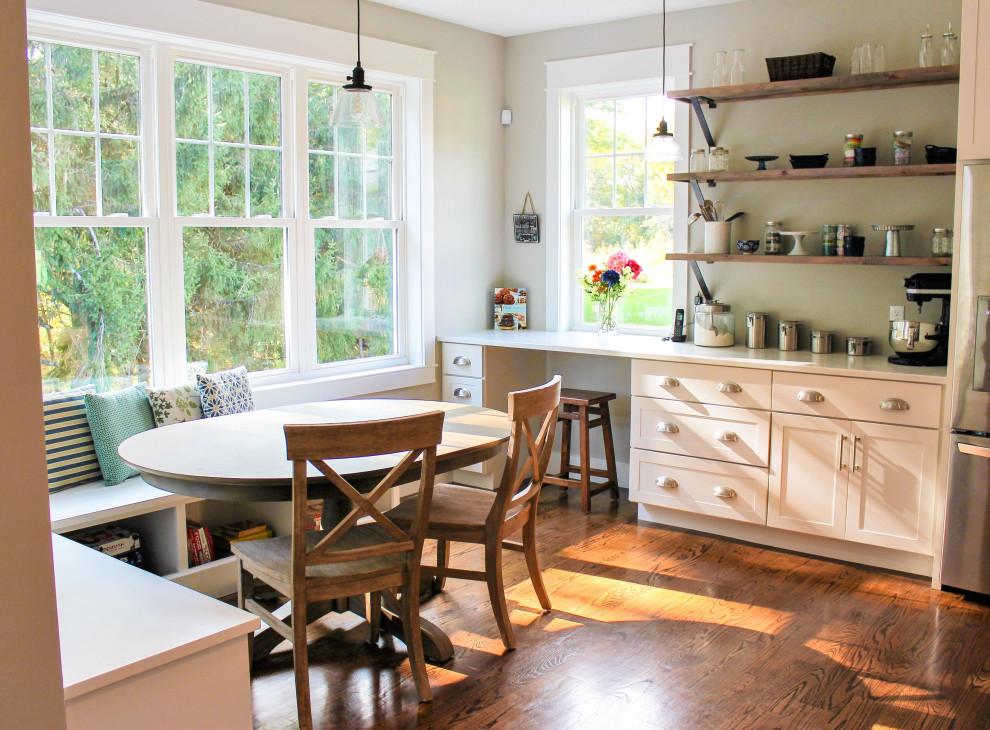 Transitional l-shaped medium tone wood floor and brown floor kitchen pantry photo with a farmhouse sink, recessed-panel cabinets, white cabinets, quartz countertops, gray backsplash, porcelain backsplash, stainless steel appliances, an island and white countertops