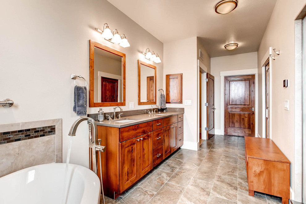 Inspiration for a mid-sized transitional gray tile and porcelain tile porcelain tile corner bathtub remodel in Denver with shaker cabinets, medium tone wood cabinets, a one-piece toilet, gray walls, an undermount sink and solid surface countertops