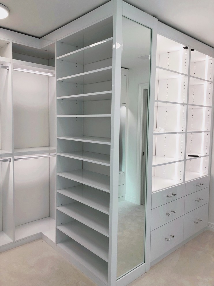 This is an example of an expansive modern women's walk-in wardrobe in Seattle with flat-panel cabinets, white cabinets, carpet and white floor.