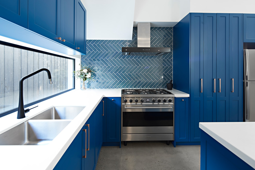 This is an example of a mid-sized transitional l-shaped kitchen pantry in Melbourne with a double-bowl sink, shaker cabinets, blue cabinets, blue splashback, ceramic splashback, stainless steel appliances, concrete floors, with island, grey floor, white benchtop and quartz benchtops.