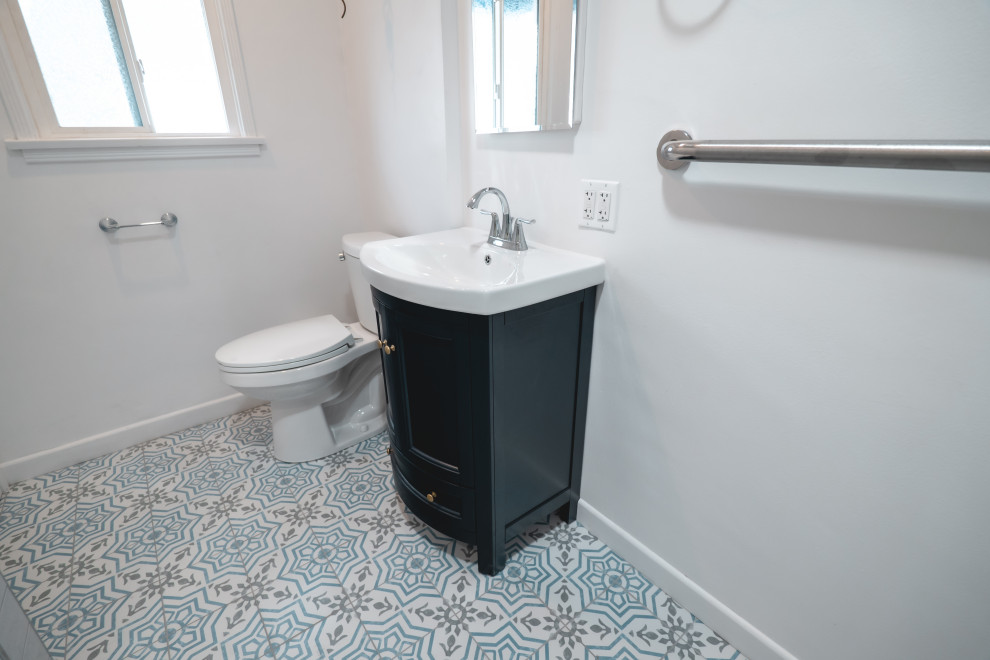 This is an example of a mid-sized modern 3/4 bathroom in Los Angeles with raised-panel cabinets, brown cabinets, a corner shower, a one-piece toilet, white tile, subway tile, white walls, cement tiles, quartzite benchtops, blue floor, a hinged shower door, white benchtops, a niche, a single vanity and a built-in vanity.