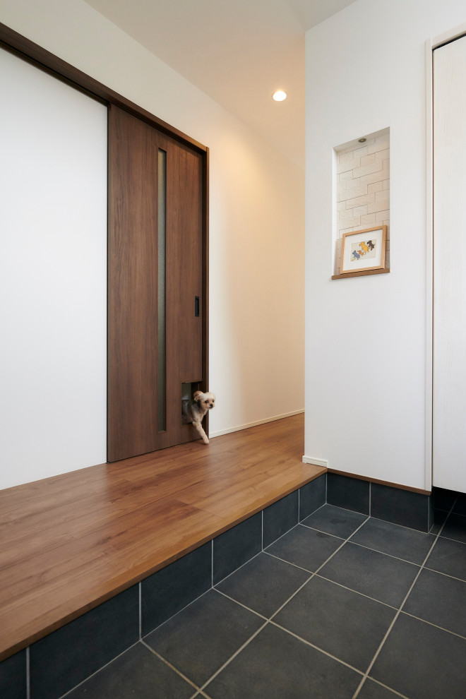 На фото: входная дверь в стиле модернизм с серыми стенами, одностворчатой входной дверью, входной дверью из темного дерева, серым полом, потолком с обоями и обоями на стенах