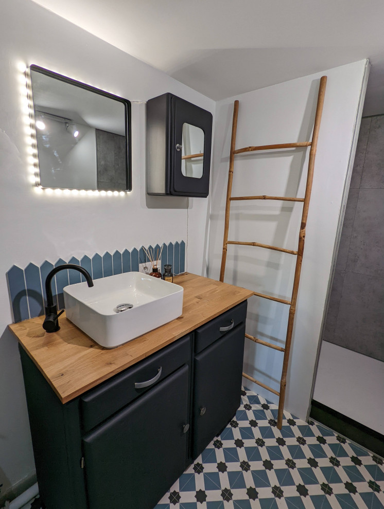 Foto på ett litet funkis flerfärgad badrum med dusch, med svarta skåp, en öppen dusch, en toalettstol med hel cisternkåpa, blå kakel, vita väggar, linoleumgolv, ett nedsänkt handfat, träbänkskiva, flerfärgat golv och med dusch som är öppen
