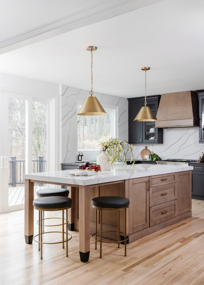 Inspiration for a transitional kitchen in Charlotte with flat-panel cabinets, black cabinets, stainless steel appliances, light hardwood floors and with island.