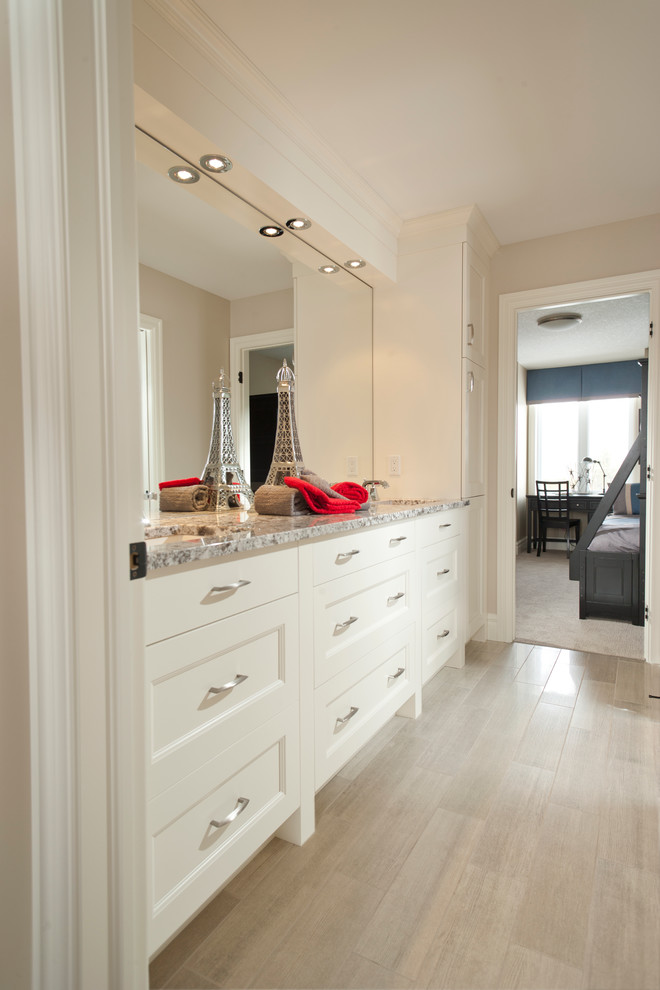 Mid-sized traditional bathroom in Toronto with recessed-panel cabinets, white cabinets, beige walls, light hardwood floors, an undermount sink and granite benchtops.
