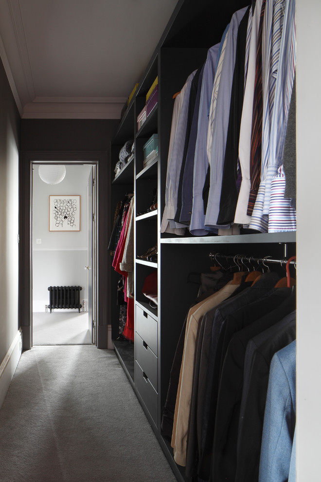 Large traditional gender-neutral walk-in wardrobe in London with open cabinets, grey cabinets, carpet, grey floor and coffered.