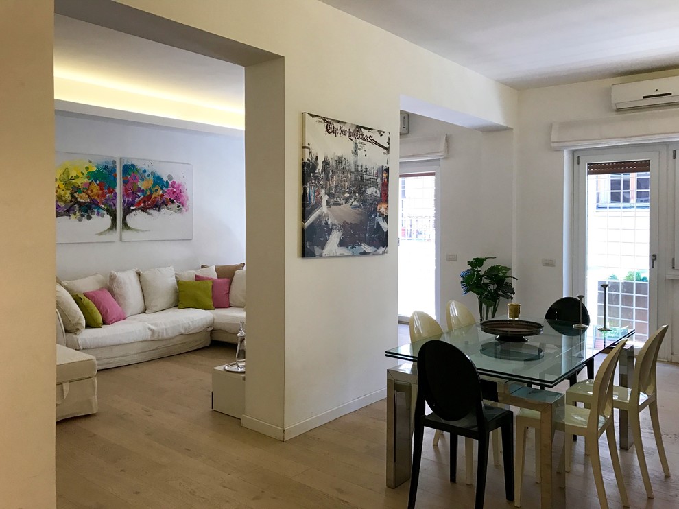 Esempio di un grande soggiorno minimal aperto con pareti bianche, parquet chiaro, cornice del camino in intonaco e TV a parete