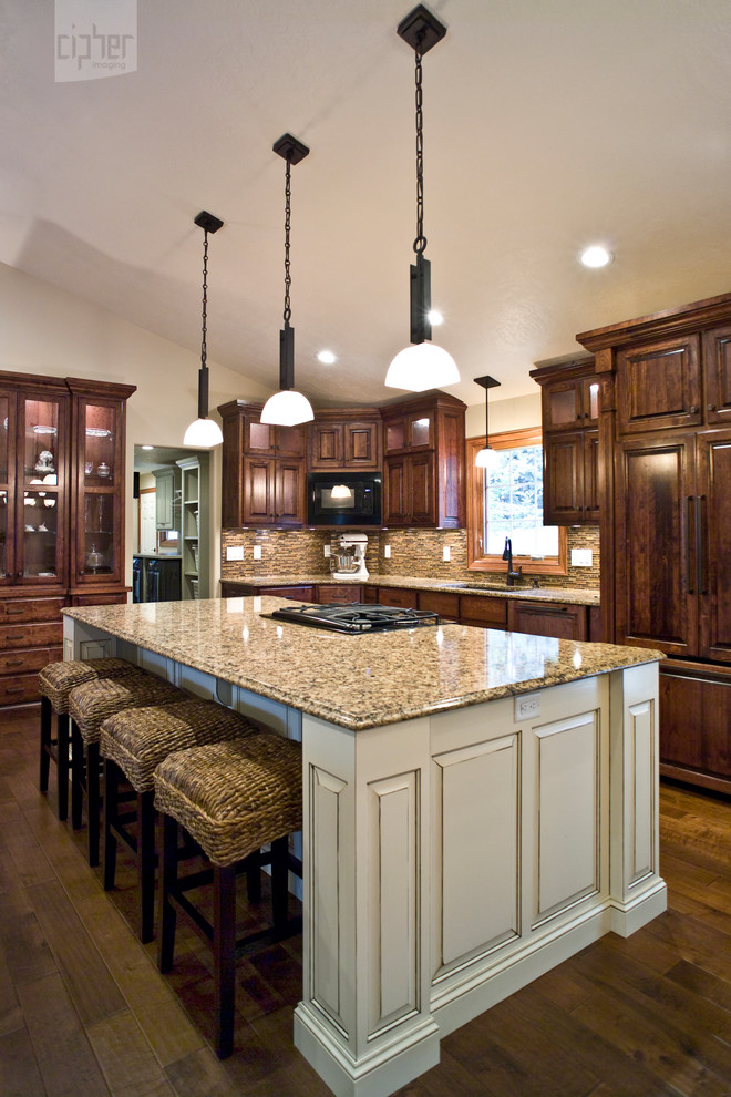 Inspiration for a mid-sized transitional l-shaped medium tone wood floor and brown floor eat-in kitchen remodel with an undermount sink, raised-panel cabinets, dark wood cabinets, granite countertops, multicolored backsplash, mosaic tile backsplash, paneled appliances and an island