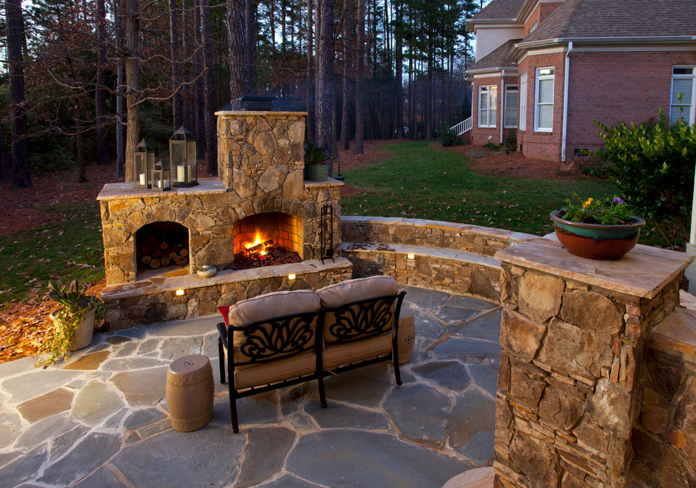 Inspiration for a mid-sized traditional backyard patio in Charlotte with with fireplace, natural stone pavers and no cover.