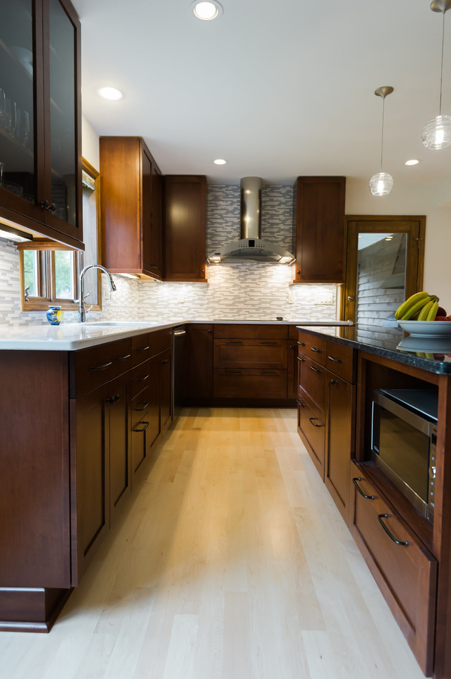 Example of a large transitional l-shaped light wood floor eat-in kitchen design with an undermount sink, shaker cabinets, dark wood cabinets, quartz countertops, gray backsplash, matchstick tile backsplash, stainless steel appliances and an island