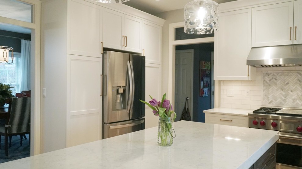 Inspiration for a transitional light wood floor open concept kitchen remodel with a farmhouse sink, recessed-panel cabinets, white cabinets, white backsplash, subway tile backsplash, stainless steel appliances, an island and white countertops