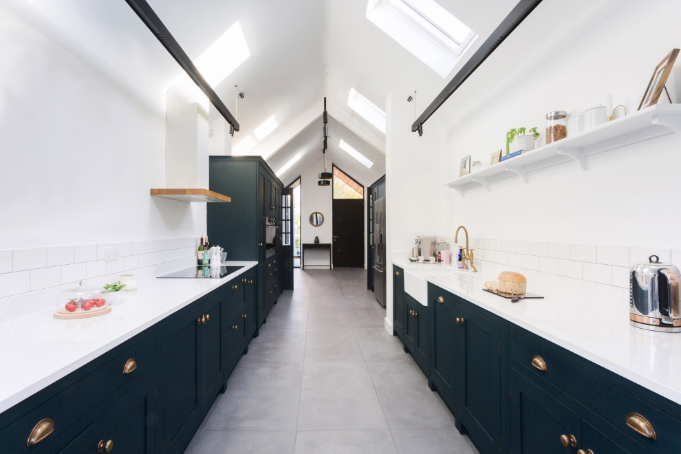Expansive transitional galley open plan kitchen in Essex with a farmhouse sink, shaker cabinets, quartzite benchtops, white splashback, cement tiles, no island, grey floor, white benchtop and blue cabinets.