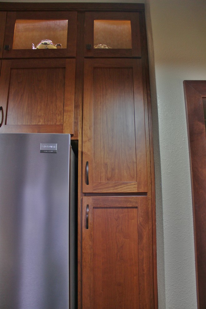 Inspiration for a mid-sized transitional galley ceramic tile enclosed kitchen remodel with an undermount sink, shaker cabinets, medium tone wood cabinets, quartz countertops, beige backsplash, stone tile backsplash, stainless steel appliances and a peninsula