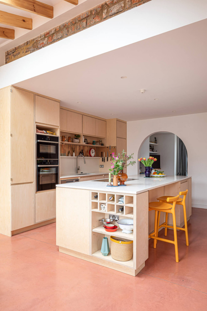 Diseño de cocina contemporánea grande abierta con armarios con paneles lisos, puertas de armario de madera clara, suelo de cemento, una isla y suelo rosa