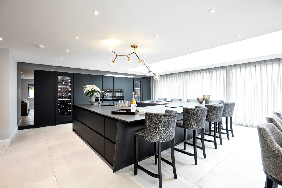 This is an example of a large contemporary u-shaped open plan kitchen in Other with a single-bowl sink, flat-panel cabinets, black cabinets, quartz benchtops, black splashback, black appliances, porcelain floors, multiple islands, grey floor and black benchtop.