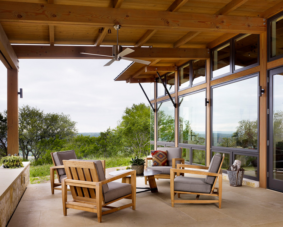 Photo of a mid-sized country side yard verandah in Austin with tile and a roof extension.