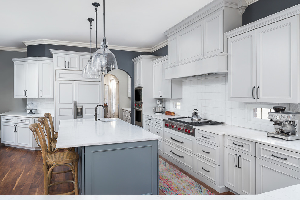 Eat-in kitchen - large transitional l-shaped medium tone wood floor and brown floor eat-in kitchen idea in Chicago with an undermount sink, white cabinets, quartz countertops, white backsplash, ceramic backsplash, stainless steel appliances, an island and white countertops