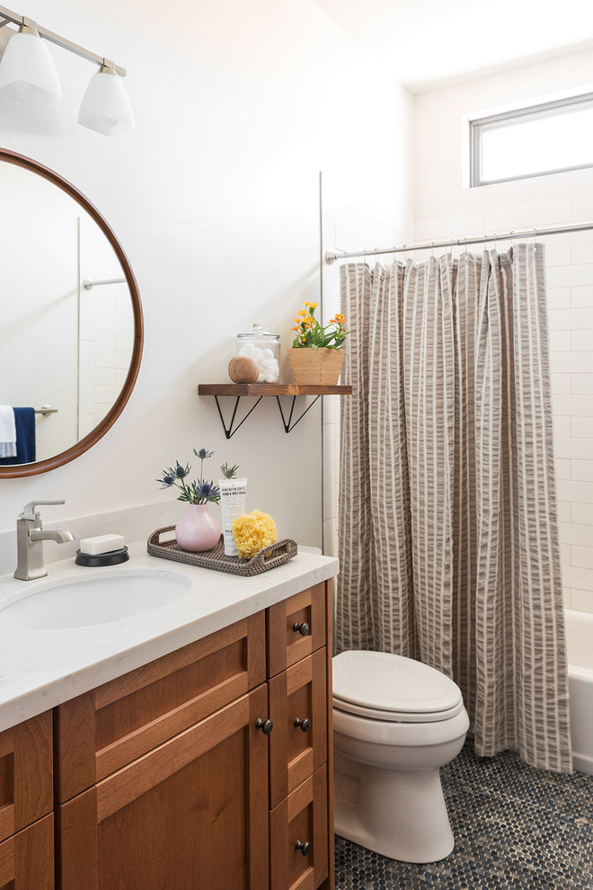 Transitional 3/4 bathroom with shaker cabinets, medium wood cabinets, an alcove tub, a shower/bathtub combo, white tile, subway tile, white walls, mosaic tile floors, an undermount sink, black floor and a shower curtain.