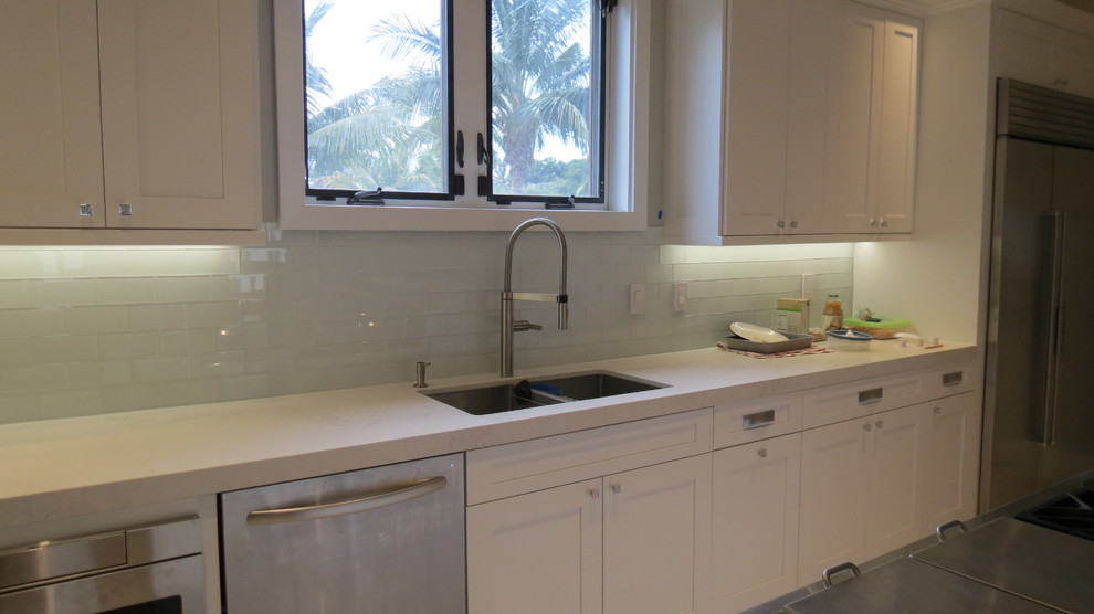 Enclosed kitchen - large transitional l-shaped light wood floor and beige floor enclosed kitchen idea with a double-bowl sink, shaker cabinets, white cabinets, marble countertops, blue backsplash, glass tile backsplash, stainless steel appliances and an island