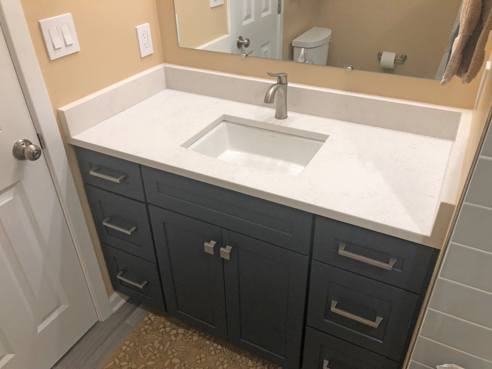 Small transitional kids bathroom in Baltimore with shaker cabinets, blue cabinets, an alcove tub, a shower/bathtub combo, a two-piece toilet, gray tile, ceramic tile, beige walls, porcelain floors, an undermount sink, engineered quartz benchtops, grey floor, a shower curtain, beige benchtops, a single vanity and a built-in vanity.