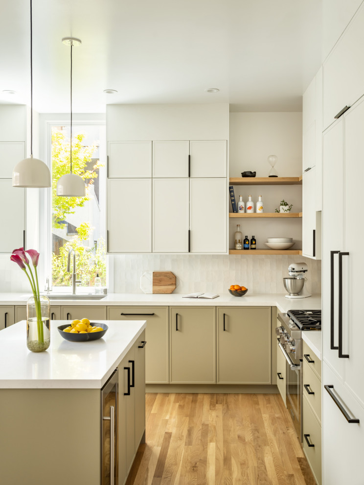 Photo of a mid-sized modern l-shaped kitchen pantry in San Francisco with an undermount sink, recessed-panel cabinets, white cabinets, quartz benchtops, grey splashback, ceramic splashback, stainless steel appliances, medium hardwood floors, with island and white benchtop.
