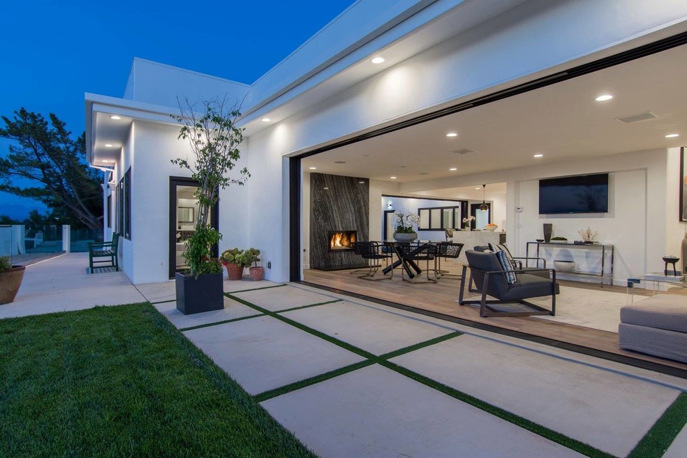 Example of a mid-sized trendy open concept medium tone wood floor and brown floor living room design in Los Angeles with white walls, a standard fireplace, a stone fireplace and a wall-mounted tv