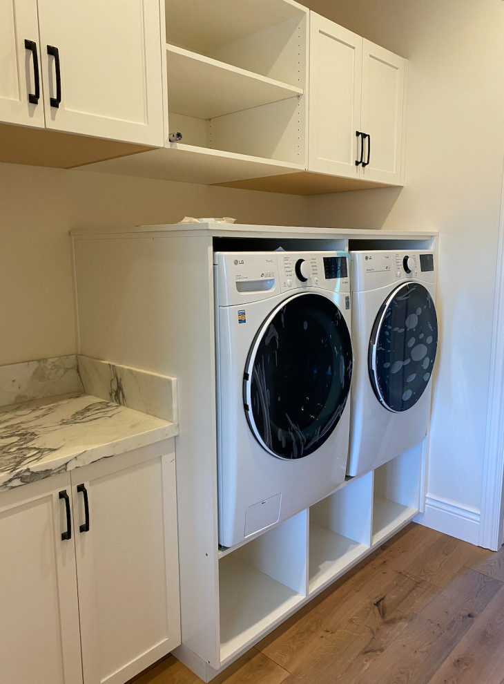 Design ideas for a small country single-wall separated utility room in San Francisco with shaker cabinets, white cabinets, marble worktops, white walls, light hardwood flooring, a side by side washer and dryer, brown floors and white worktops.