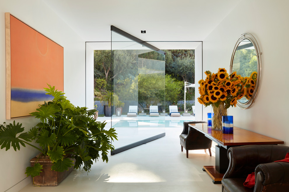 Photo of a midcentury foyer in Los Angeles with white walls, a pivot front door, a gray front door and white floor.