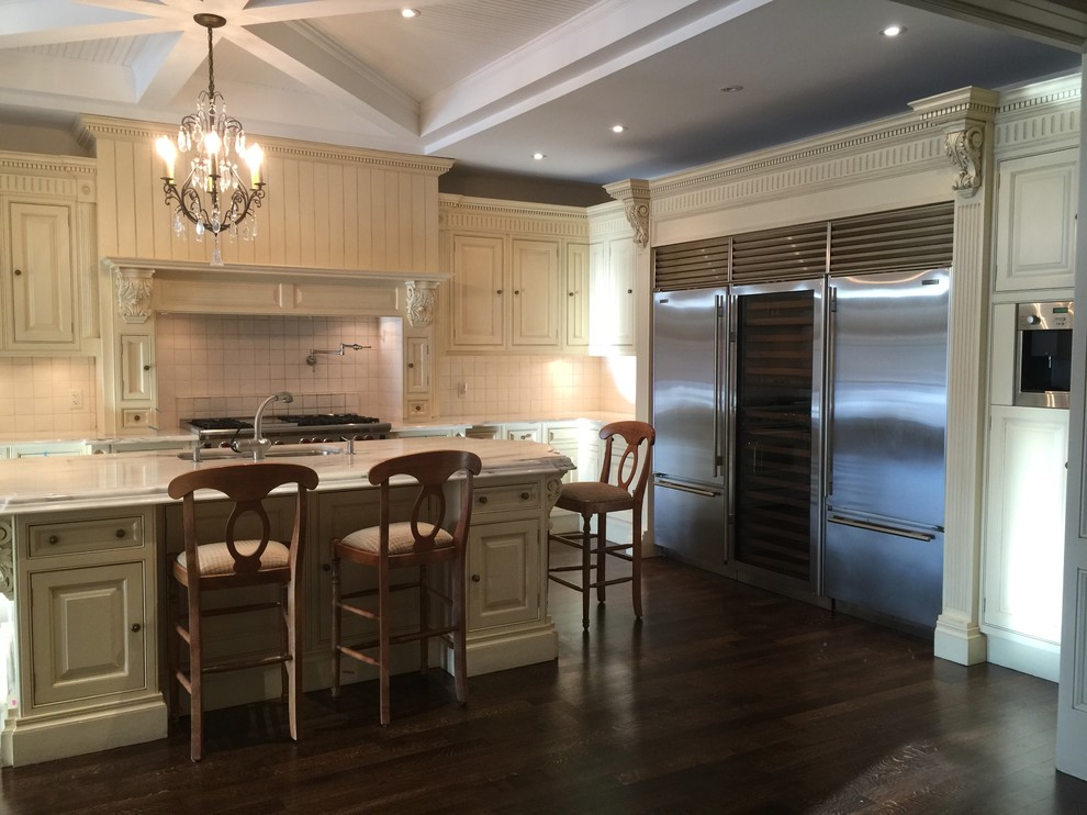 Example of a large transitional l-shaped dark wood floor open concept kitchen design in Toronto with a double-bowl sink, raised-panel cabinets, beige cabinets, white backsplash, stainless steel appliances and an island
