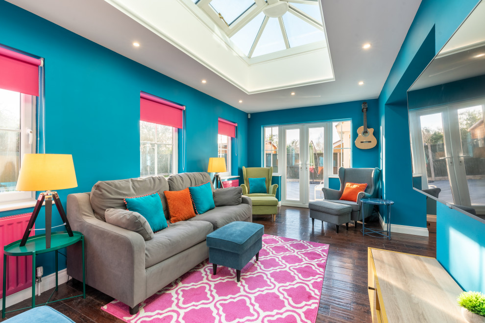 Esempio di un grande soggiorno design aperto con pareti blu, parquet scuro, TV a parete, pavimento marrone e libreria
