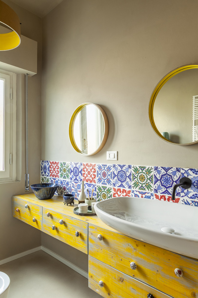 Medelhavsstil inredning av ett mellanstort gul gult badrum med dusch, med skåp i shakerstil, gula skåp, en dusch i en alkov, en toalettstol med separat cisternkåpa, flerfärgad kakel, keramikplattor, beige väggar, betonggolv, ett fristående handfat, träbänkskiva, beiget golv och dusch med gångjärnsdörr
