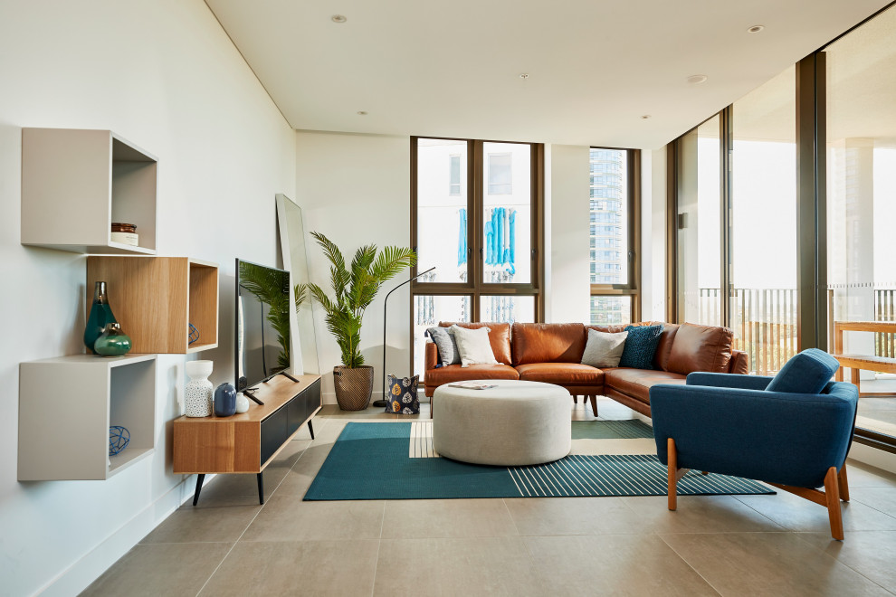 This is an example of a large contemporary open concept living room in Melbourne with white walls, a freestanding tv and grey floor.
