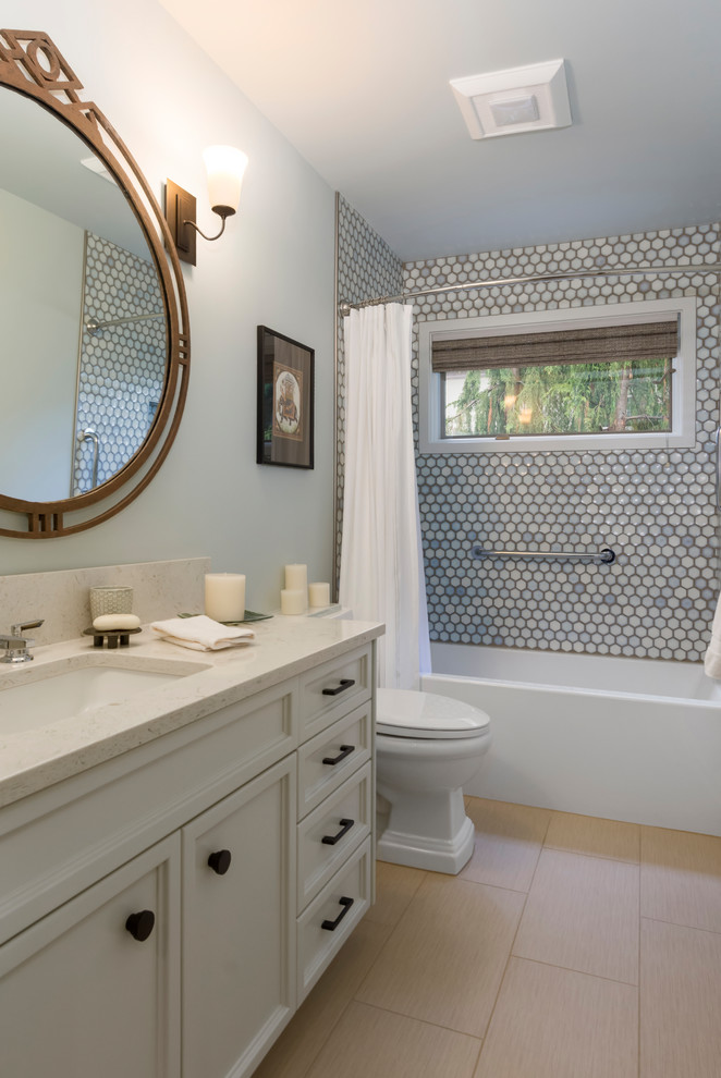 This is an example of a mid-sized transitional bathroom in Seattle with recessed-panel cabinets, grey cabinets, an alcove tub, a shower/bathtub combo, a one-piece toilet, gray tile, porcelain tile, grey walls, porcelain floors, an undermount sink, engineered quartz benchtops, beige floor and a shower curtain.